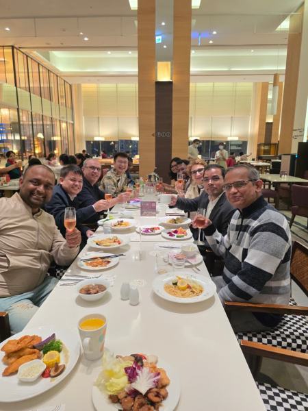 Guests raise their glasses for a toast along a long table in a hotel restaurant.