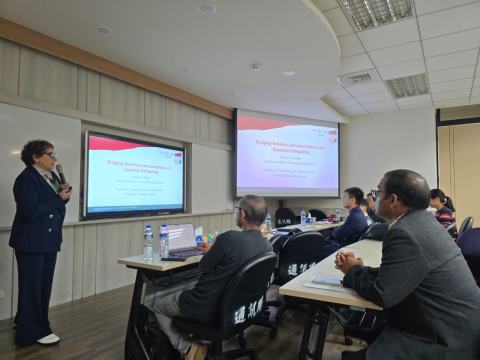 A speaker presents the title slide “Bridging Wireless Communications and Quantum Computing” to workshop attendees in the seminar room.
