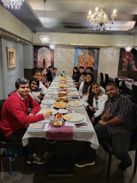 Lab members seated along a long dinner table, seen from one end.