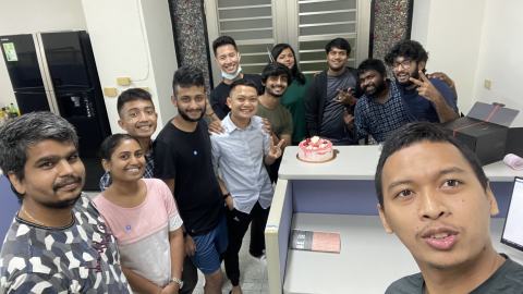 Selfie of lab members gathered around a cake in the lab.